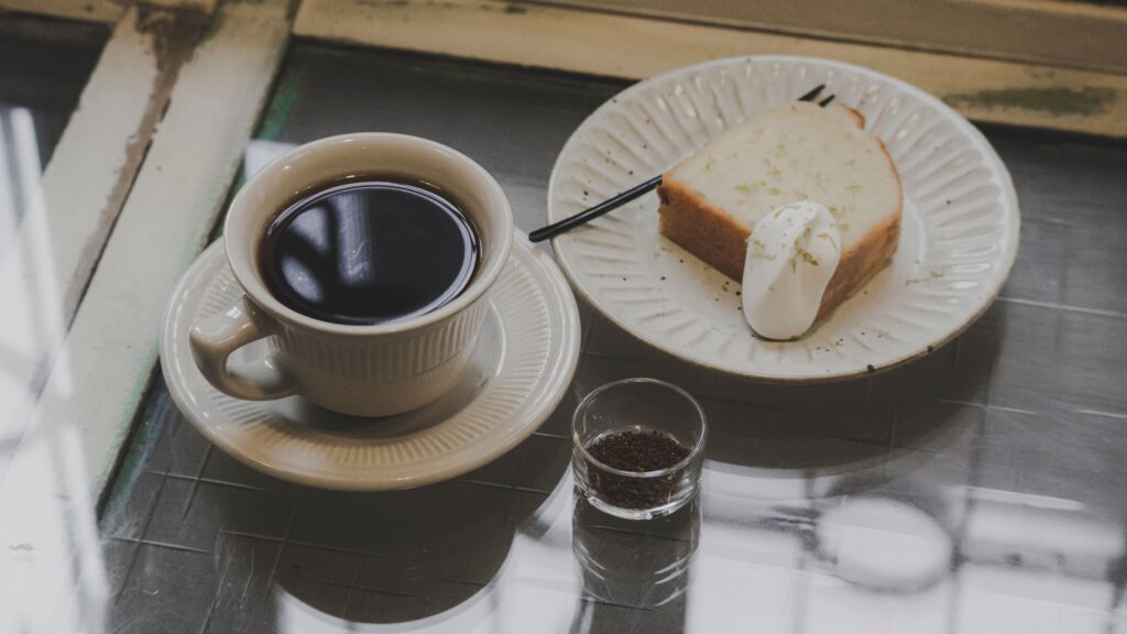 A stylish breakfast scene with black coffee and cake on a ceramic plate, perfect for food enthusiasts.
